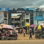 A busy market with Infinix and TECNO sign posts